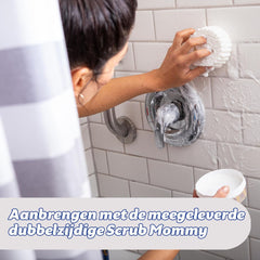Woman using Scrub Mommy and Power Paste to clean tiled bathroom shower wall