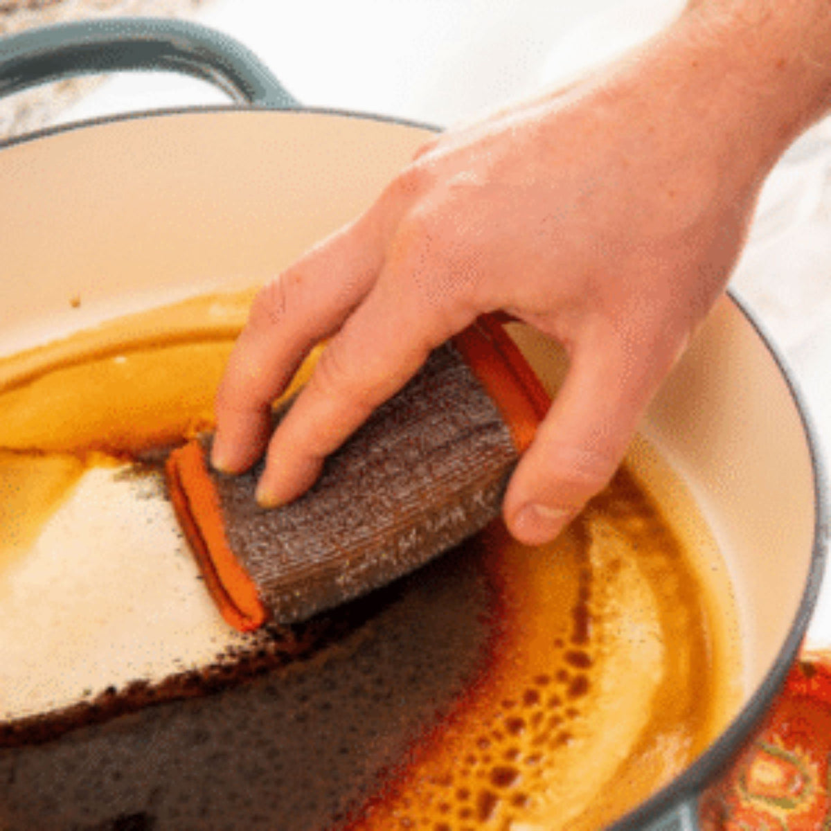 Person scrubbing a pot with a sponge